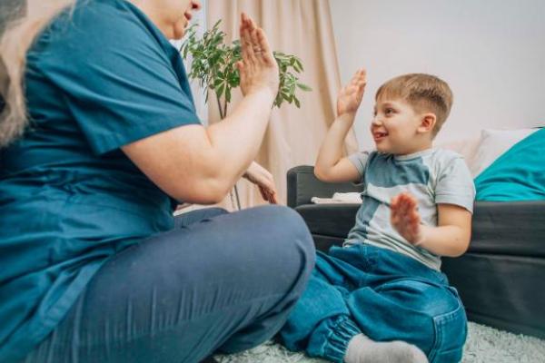 Child hi-fiving an adult sat cross legged on the floor