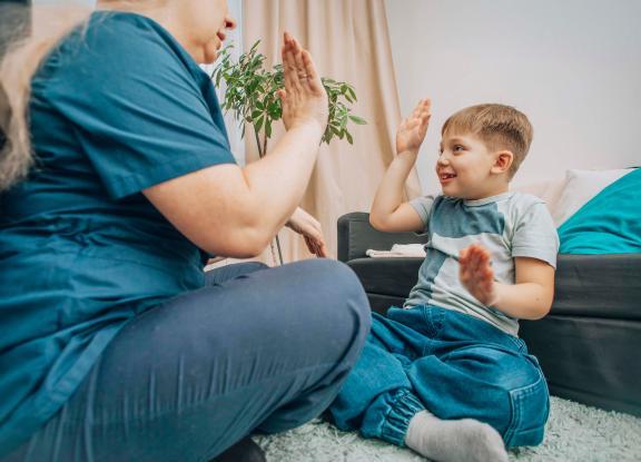 Child hi-fiving an adult sat cross legged on the floor